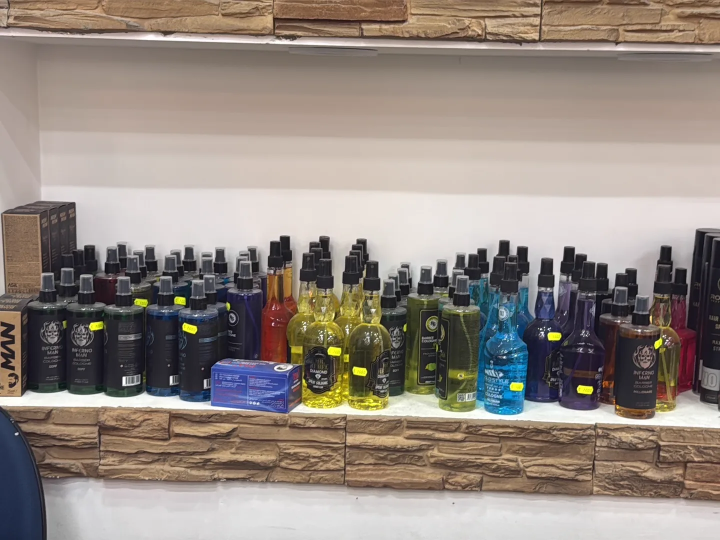 Regal mit Barber-Colognes an der Steinwand im Salon